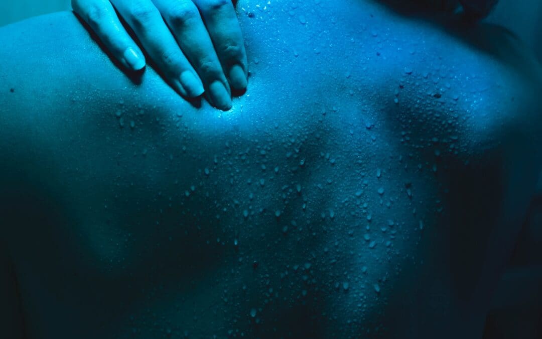 A hand touching someone's upper back with back pain.