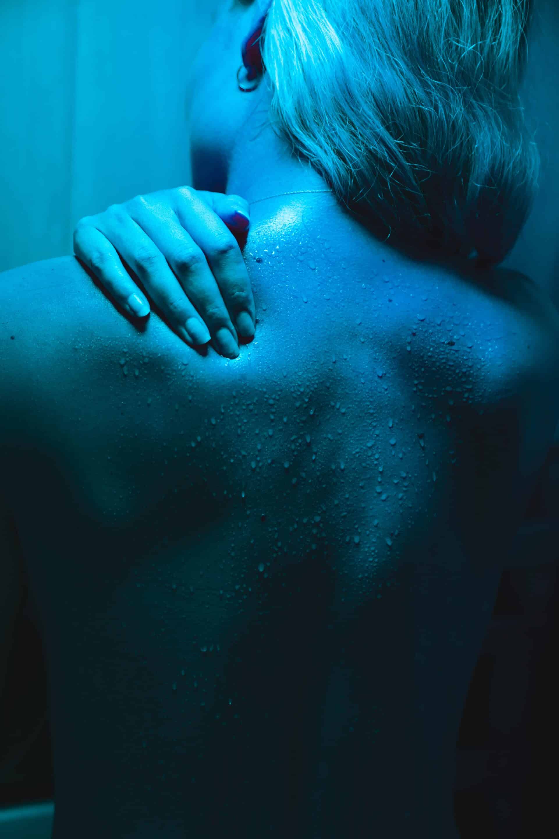 A hand touching someone's upper back with back pain.